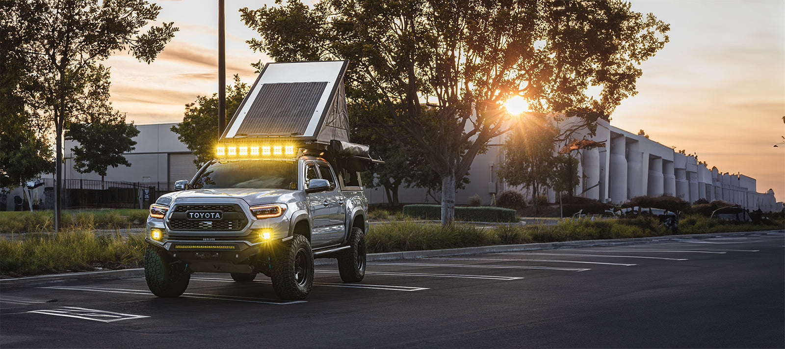 toyota tacoma parked in a parking lot in an industrial area with the roof top camper tent open